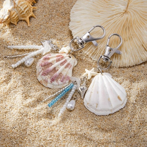 Ocean shell pearl keychain set with starfishes and beads on a beach sand background