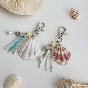 Detail of ocean-themed seashell keychains with pearls and blue beaded tassels on coral