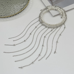 Detail einer mehrlagigen Kette mit weißen Perlen und silbernen Metallfransen-Quasten