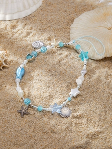 Detailed beach scene of a sea-themed phone strap with starfish and shell pendants