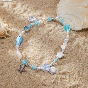 Bijou de téléphone océan avec perles bleues, étoile de mer et coquillage sur le sable