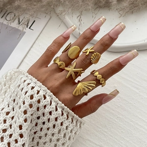 Close-up of gold starfish and seashell stacking rings set on hand for vacation style
