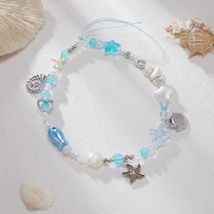 Bijou de téléphone océan avec perles d'étoile de mer et coquillages sur sable