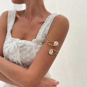 Detail view of a gold wire bohemian arm cuff with two natural white cowrie shells