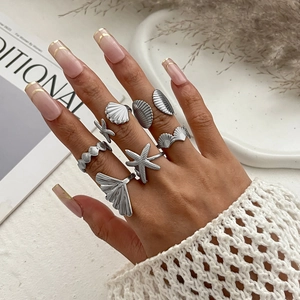 Close-up of bohemian silver starfish and seashell ring set on model's hand