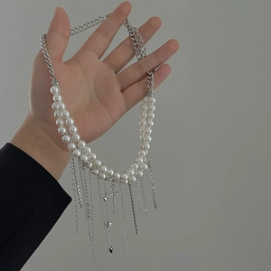 Details einer mehrlagigen Perlenkette mit silbernen Quasten und Anhängern