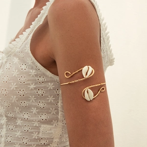 Boho golden wire arm cuff featuring two cowrie shells on a female model arm