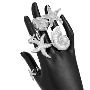 Detail view of silver ocean style rings with sea stars and pearls on a black hand model