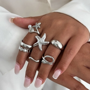 Detail of silver starfish and seashell ring set on model hand for beach vacation style