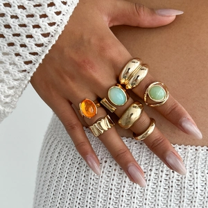 Close-up of stacked gold rings set with colorful gemstones and hammered metal texture