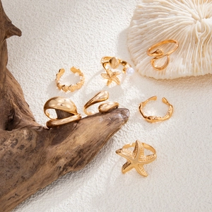 Detail of 7-piece gold ocean theme ring set featuring starfish shells and pearls