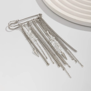 Close-up of silver punk brooch with long metal fringe, crystals and spiked charms