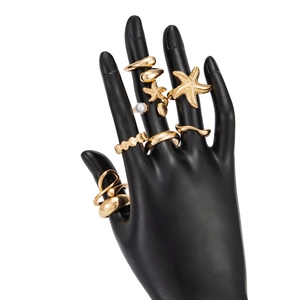 Close-up of golden starfish and seashell ring set with pearls on a black hand display