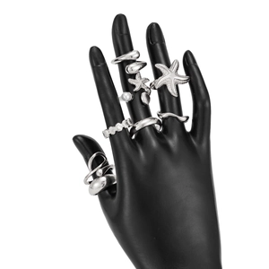 Silver marine ring set featuring starfish and seashell charms on a black hand model