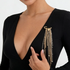 Detail einer goldenen Brosche mit langen Ketten und Herzanhängern im Boho-Stil