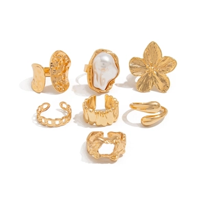 7-teiliges Goldring-Set mit Barockperlen und Blumen-Design auf weißem Hintergrund
