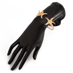 Nahaufnahme des goldenen Seestern-Armreifs mit körniger Textur auf einem schwarzen Handmodell