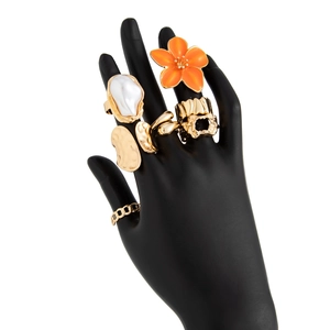 Detailopname van gouden bloem- en barokke parelringen op een zwart handmodel