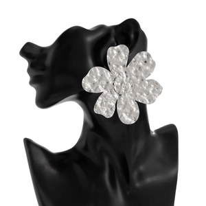 Dettaglio del grande orecchino a fiore in argento con texture martellata lucida