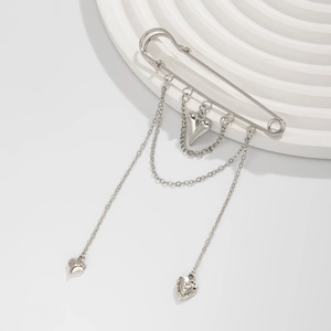 Detail of silver heart tassel brooch with triple chains and engraved charms on white stand