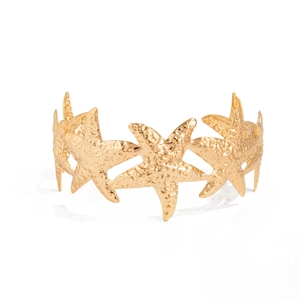 Detailansicht eines goldenen Seestern-Armreifs mit gehämmerter Textur und Finish