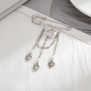 Detail of vintage silver heart pendant brooch with metal chains and faux pearls