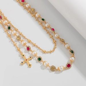 Close-up of golden pant chain with colorful gemstones, pearls and cross pendant