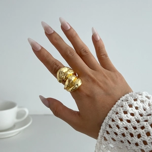Détail d'une bague dorée épaisse style lave avec texture ondulée irrégulière