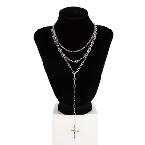 Dettaglio collana argentata a strati con gemme colorate e ciondolo a croce
