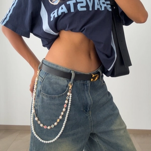 Detail of double-layer pant chain with colorful gemstones and pearls on denim jeans