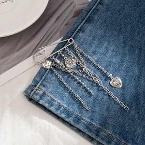 Silver multi-layer chain brooch with heart charms pinned on blue denim jacket