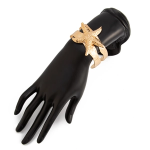 Detail eines breiten goldenen Seestern-Armreifs an einem schwarzen Handmodell