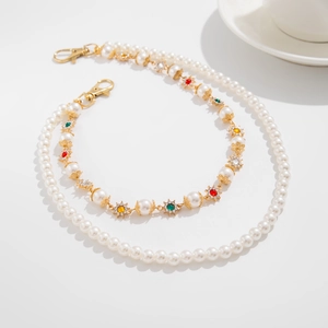 Detail of punk hip hop trousers chain featuring colorful pearls and a cross charm