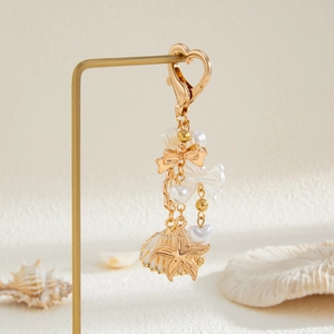 Detail of gold keychain with seashell, starfish charms and elegant white pearls