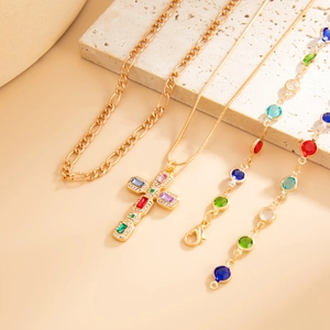 Dettaglio di collane e bracciali dorati con pendente a croce in cristalli colorati