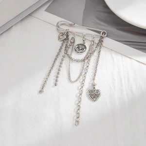Silver vintage multi-layered pin with heart charms and metal chains on white fabric