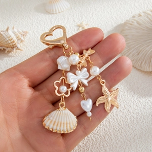 Macro shot of sea-themed keychain with heart clasp, pearls and golden starfish charms