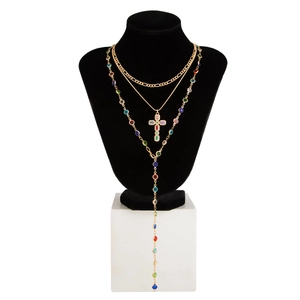 Dettaglio collana tripla dorata con pietre multicolori e ciondolo a croce elegante