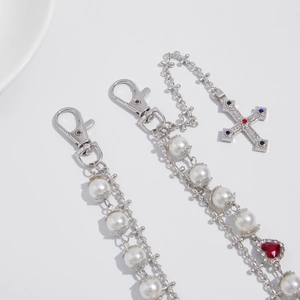 Detail view of silver punk chain with faux pearls, crystal cross, and red heart charm