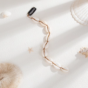 Détail d'une extension de cheveux bohème en coquillages avec un clip en métal noir