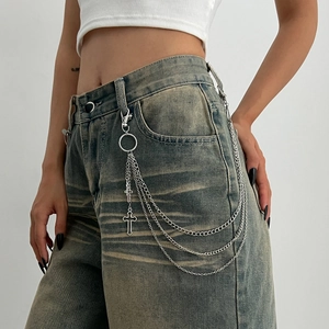 Detail of multi-layer silver metal waist chain with cross pendant on denim jeans