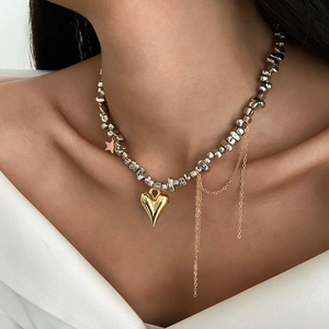 Primo piano della collana di perle con pendente a cuore d'oro e nappa sulla modella