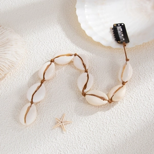 Détail de bijoux de cheveux en coquillages avec épingle en U sur fond de plage blanc