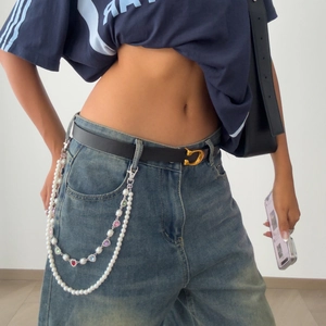 Detail view of pearl hip chain with colorful heart-shaped gems on denim pants