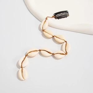Détail d'une pince à cheveux bohème avec coquillages naturels sur cordon tressé