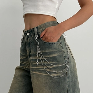 Close-up of triple-layered silver waist chain with star pendants and ring on denim jeans
