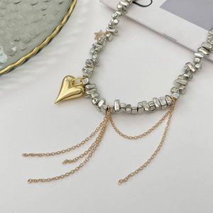 Dettaglio collana di perline d'argento con grande ciondolo a cuore dorato e nappe lunghe