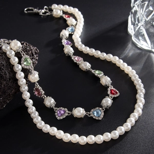 Detailed shot of multi-color heart gemstones and pearls on punk hip-hop cross pants chain