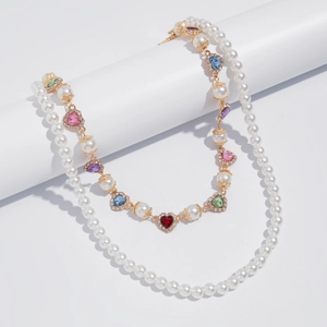 Detail of double-layer pearl necklace with colorful heart gems and golden accents