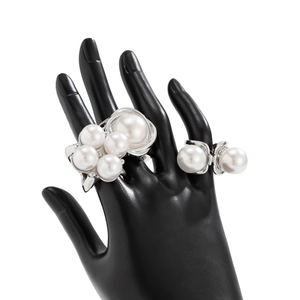 Detail of chunky cluster faux pearl and dual pearl rings on a black jewelry hand stand
